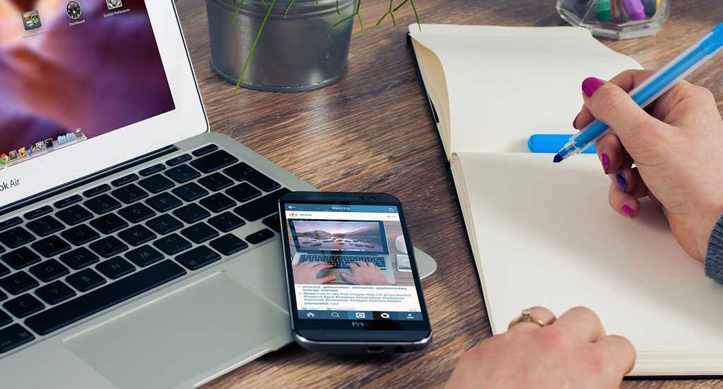 Older woman writing in a notepad while job hunting online