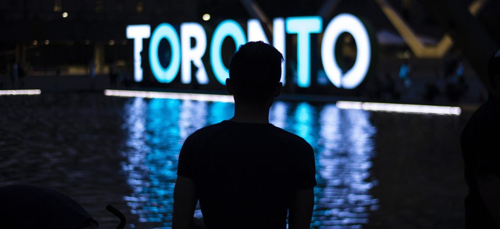 Man standing in front of the Toronto sign