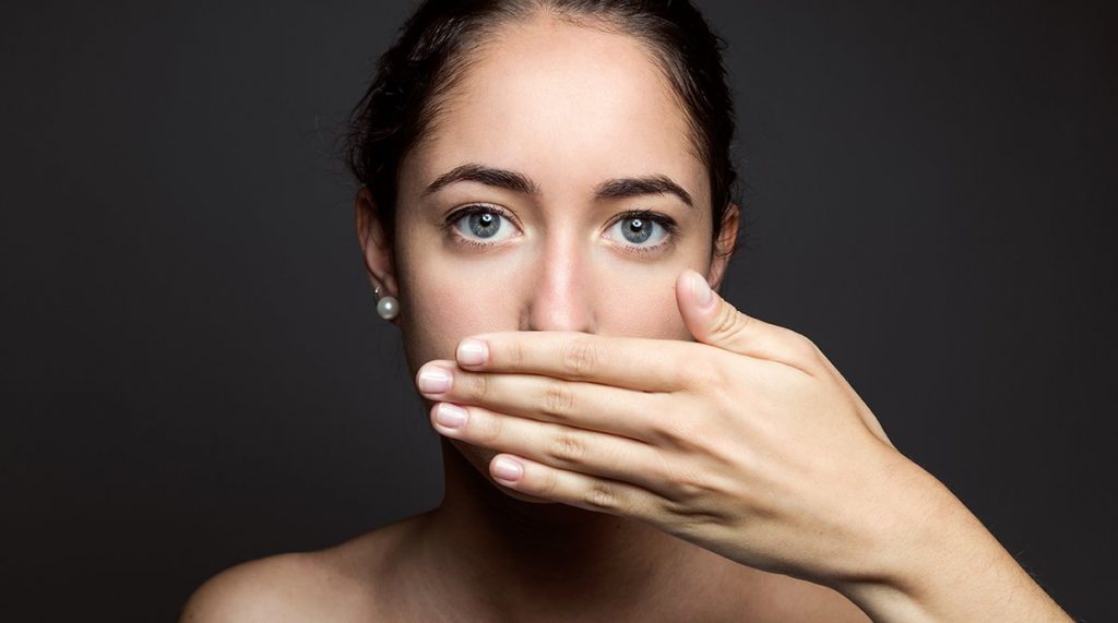 Woman with hand over her mouth, looking pensive