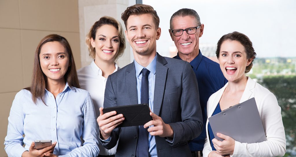 Group of five happy business people standing in conference room and smiling at camera. 