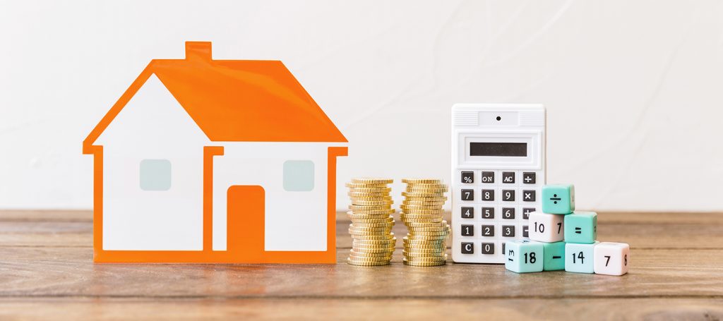 House, stacked coins and calculator sitting on a table