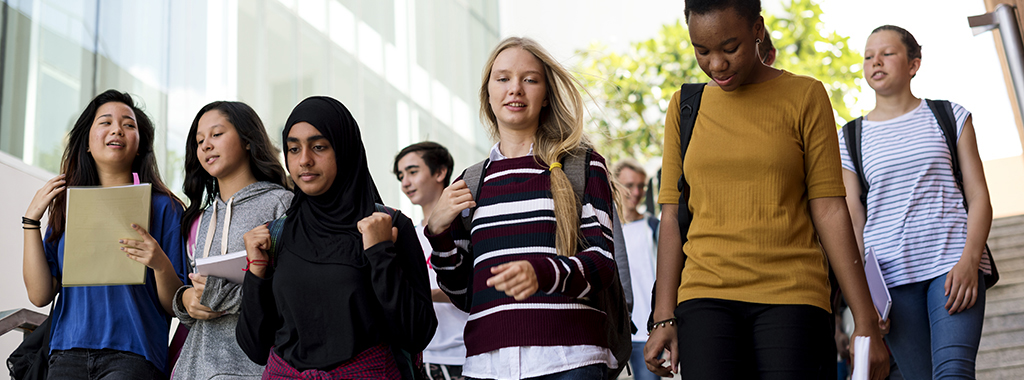 Diverse group of young students walking in school