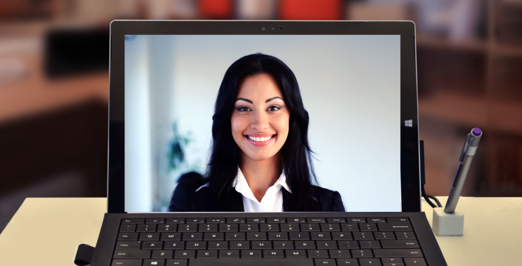 A woman appearing on a laptop top screen in a video