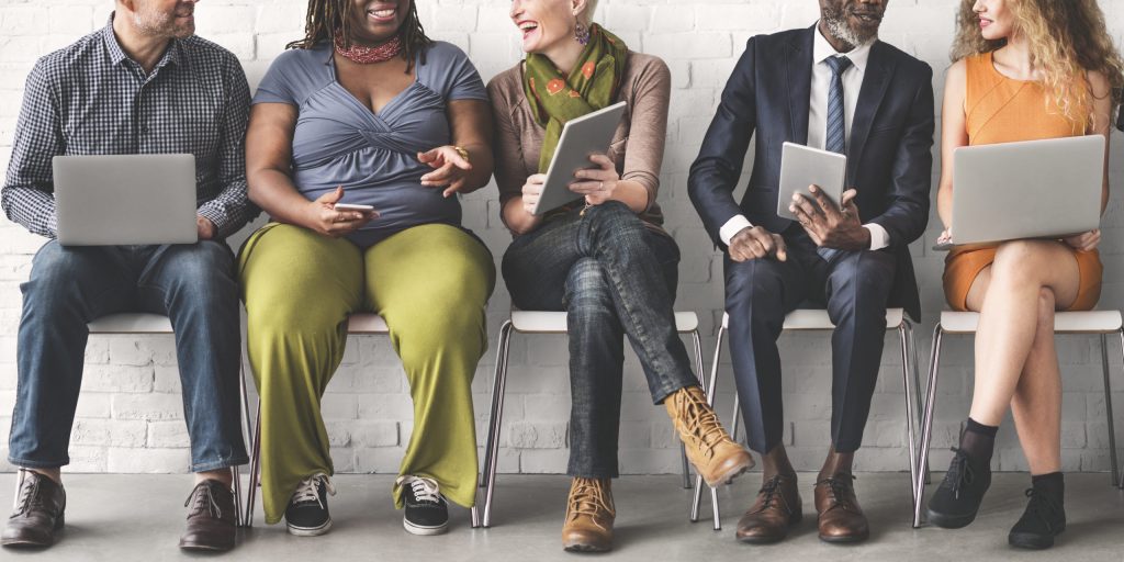 A group of diverse people using digital devices and talking together