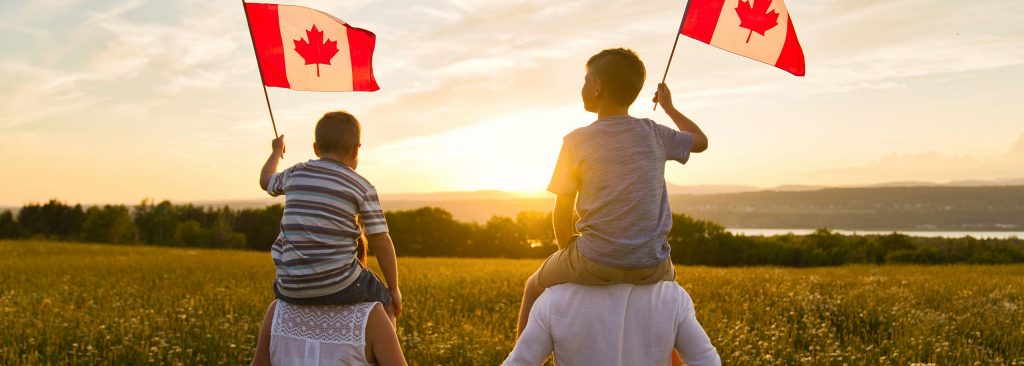 Adorable cute Caucasian boys holding Canadian flag on the father shoulder