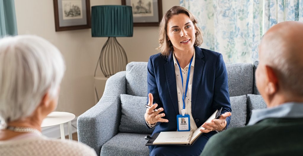 Social worker, talking to old man and woman for insurance plans on retirement. Happy supporter with senior people during a home consultation: counselling and psychological session at home.