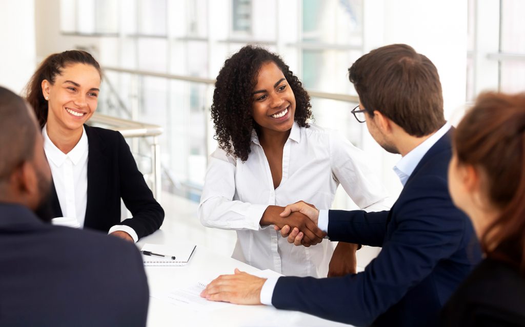 Multiracial businessman businesswoman shake hands starting collaboration at group negotiations, positive people gathered at modern office boardroom, partnership teamwork and business etiquette concept