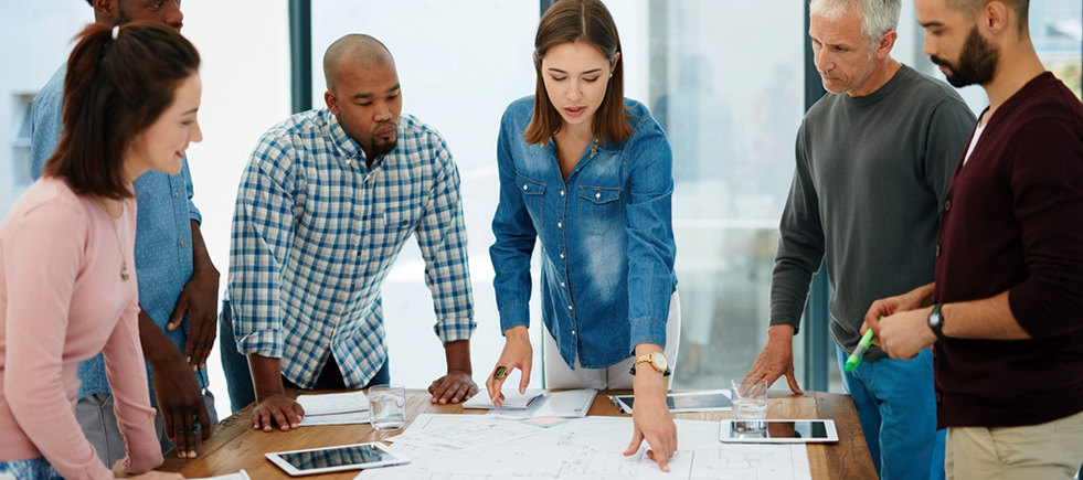 Multi ethnic people working with laptop, tablet and building model for architecture project.